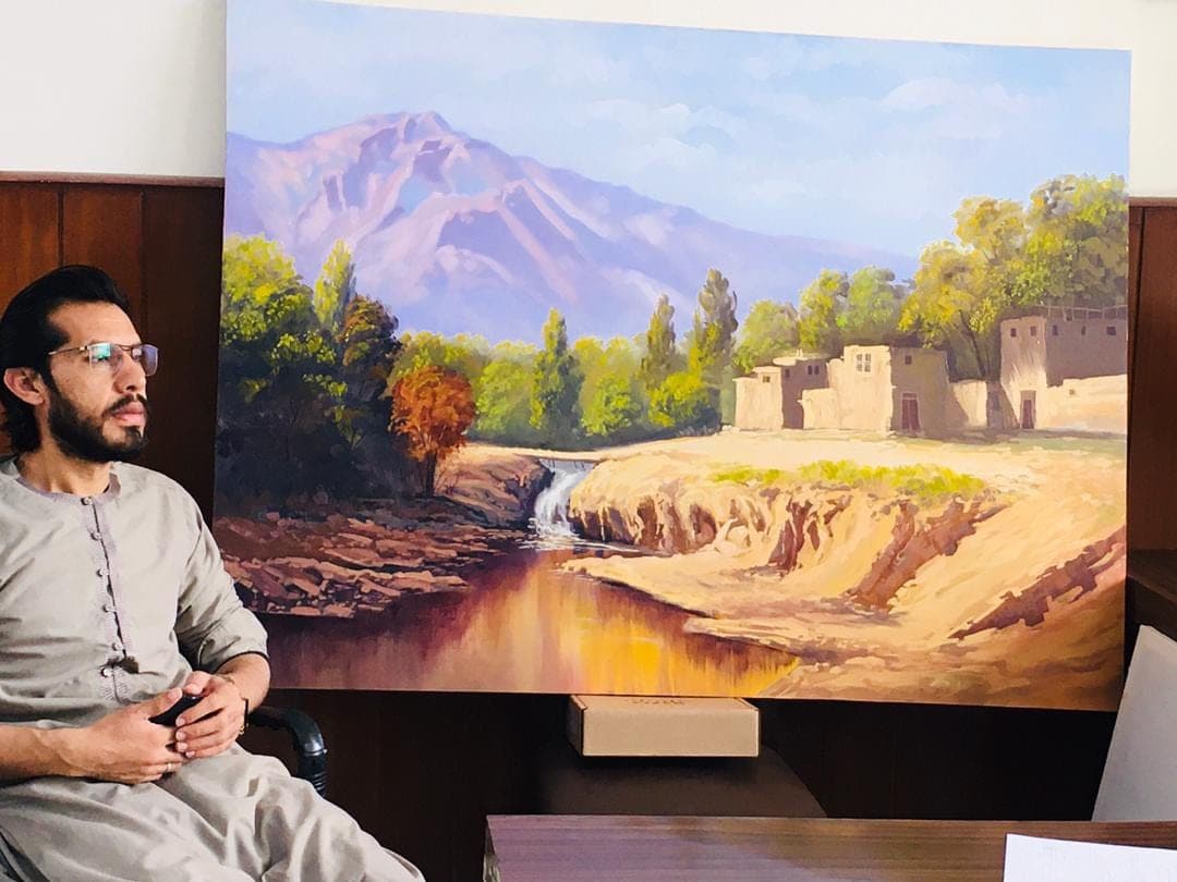 The artist seated in front of a finished landscape painting